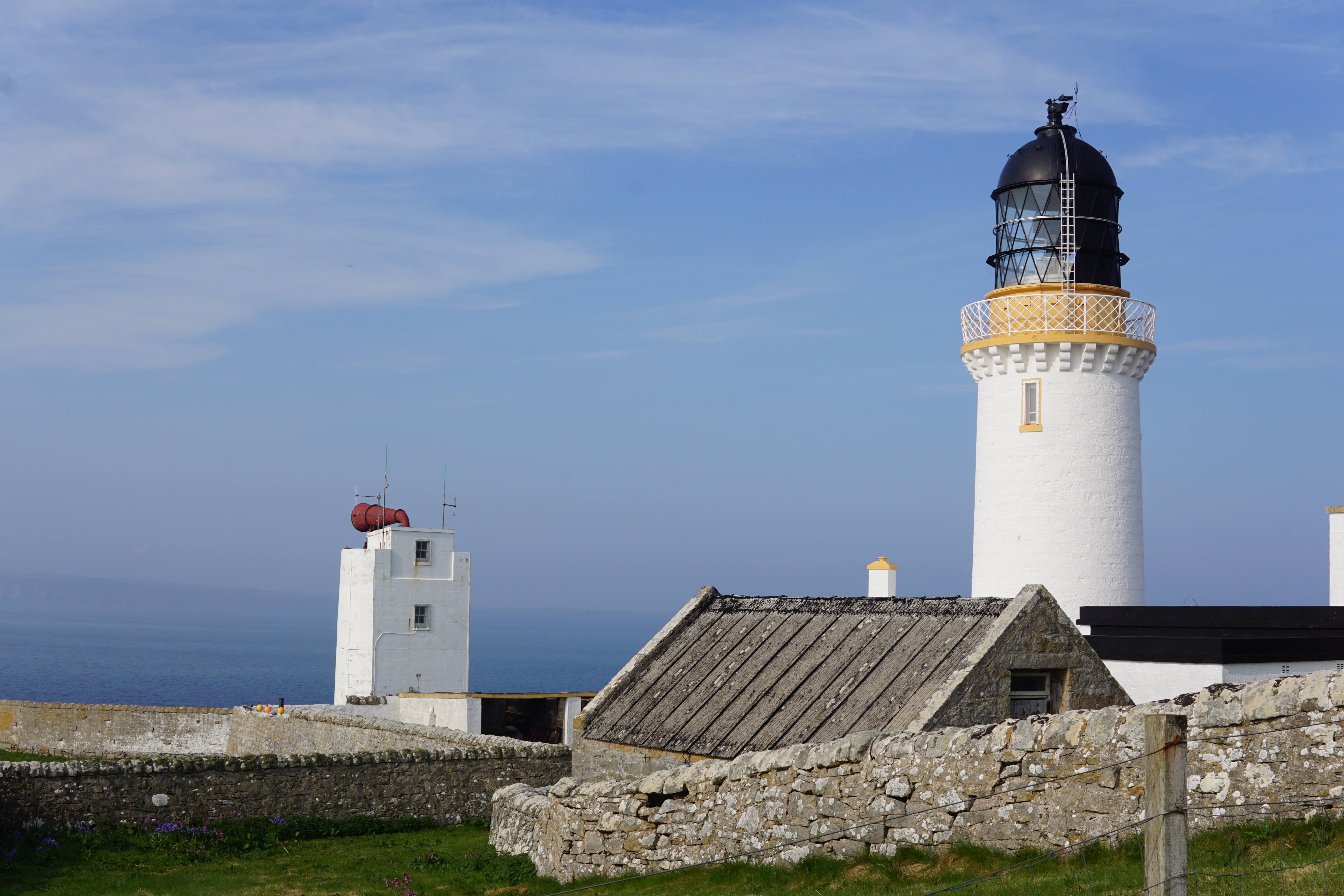 Lighthouse located at very top of NC500. Blue sky in distance.