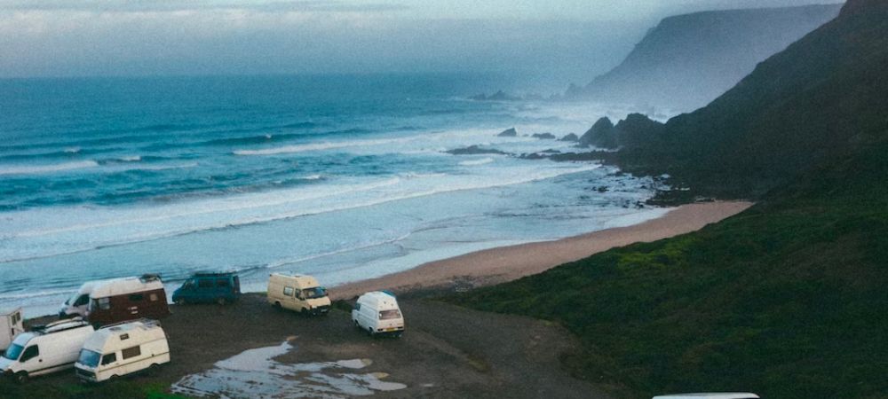 An image of a collection of campervans next to a beach